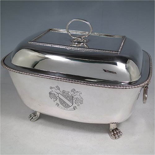 An Antique Georgian Sterling Silver soup tureen, having a plain rectangular body with rounded corners, a pull-off lid cover with an asparagus loop handle, with applied gadroon borders, two cast lion-mask loop side handles, and all sitting on four cast lions-paw feet. Made by William Bennett of London in 1805. The dimensions of this fine hand-made antique silver soup tureen and cover are height 21 cms (8.25 inches), length 28 cms (11 inches), width 20 cms (8 inches), and it weighs approx. 1,860 (60 troy ounces). Please note that this antique soup tureen is crested on one side.