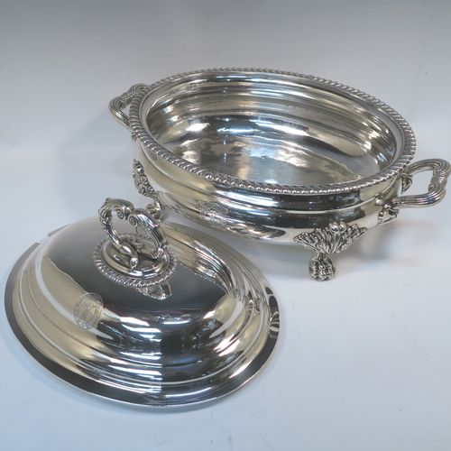 A very handsome Antique Georgian Sterling Silver Scottish soup tureen in a Regency style, having an oval plain baluster body with applied gadroon border, a domed pull-off cover with a cast anthemion leaf handle, with two cast scroll side handles, and sitting on four cast lions-paw feet with floral shoulders. This elegant antique silver soup tureen and cover was made in Edinburgh in 1815. The dimensions of this fine hand-made antique silver soup tureen are height 24 cms (9.5 inches), and width (across handles) 42 cms (16.5 inches), and it weighs approx. 3,285g (106 troy ounces). Please note that this antique Regency silver soup tureen is crested on the main body and cover.