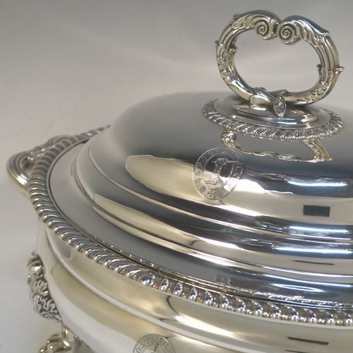 A very handsome Antique Georgian Sterling Silver Scottish soup tureen in a Regency style, having an oval plain baluster body with applied gadroon border, a domed pull-off cover with a cast anthemion leaf handle, with two cast scroll side handles, and sitting on four cast lions-paw feet with floral shoulders. This elegant antique silver soup tureen and cover was made in Edinburgh in 1815. The dimensions of this fine hand-made antique silver soup tureen are height 24 cms (9.5 inches), and width (across handles) 42 cms (16.5 inches), and it weighs approx. 3,285g (106 troy ounces). Please note that this antique Regency silver soup tureen is crested on the main body and cover.