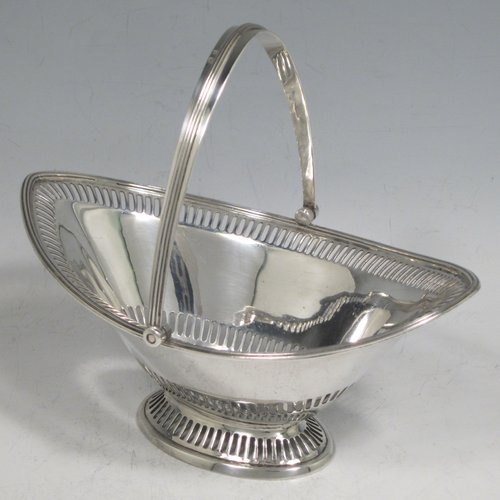 Antique Edwardian sterling silver sugar or sweetmeat basket, having an oval body, with an upper and lower band of hand-pierced decoration, an applied reeded border, a reeded swing-handle, and sitting on a pedestal foot with matching piercing. Made by Walker & Hall of Birmingham in 1910. The dimensions of this fine hand-made silver sugar basket are height 14.5 cms (5.75 inches), length 16.5 cms (6.5 inches), width 11 cms (4.25 inches), and it weighs approx. 176g (5.7 troy ounces).    