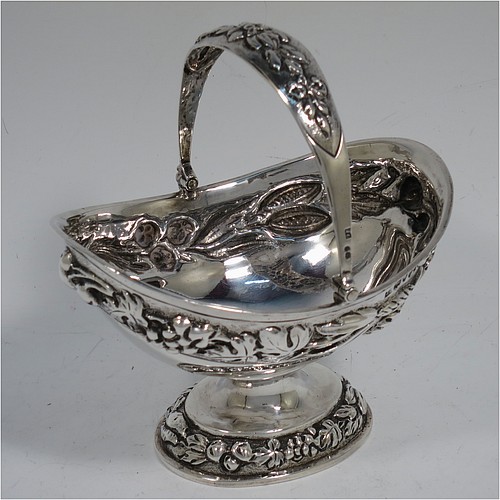 A very pretty Antique Victorian Sterling Silver sugar basket, having an oval shaped body, a swing-handle, and sitting on a pedestal foot, all hand-chased with floral and fruit decoration. Made by Jacobes J. Oasterbaan of London in 1878. The dimensions of this fine hand-made antique silver sugar basket are height 12.5 cms (5 inches), length 11.5 cms (4.5 inches), width 9 cms (3.5 inches), and it weighs approx. 192g (6.2 troy ounces).    