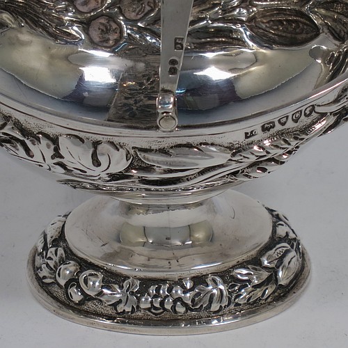 A very pretty Antique Victorian Sterling Silver sugar basket, having an oval shaped body, a swing-handle, and sitting on a pedestal foot, all hand-chased with floral and fruit decoration. Made by Jacobes J. Oasterbaan of London in 1878. The dimensions of this fine hand-made antique silver sugar basket are height 12.5 cms (5 inches), length 11.5 cms (4.5 inches), width 9 cms (3.5 inches), and it weighs approx. 192g (6.2 troy ounces).    