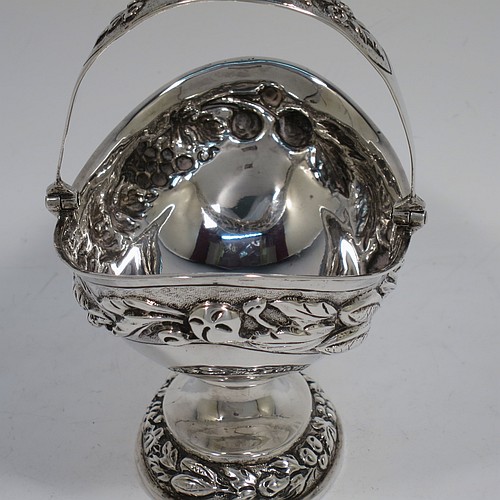 A very pretty Antique Victorian Sterling Silver sugar basket, having an oval shaped body, a swing-handle, and sitting on a pedestal foot, all hand-chased with floral and fruit decoration. Made by Jacobes J. Oasterbaan of London in 1878. The dimensions of this fine hand-made antique silver sugar basket are height 12.5 cms (5 inches), length 11.5 cms (4.5 inches), width 9 cms (3.5 inches), and it weighs approx. 192g (6.2 troy ounces).    