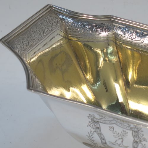 A lovely Antique Georgian Sterling Silver sugar basket, having a shaped rectangular and panelled  body with cut-corners, an applied reeded top border above a band of hand-engraved floral and scroll decoration, a gold-gilt interior, and sitting on a matching pedestal foot. Made by William Frisbee of London in 1794. The dimensions of this fine hand-made antique silver sugar basket are height 14.5 cms (5.75 inches), length 10 cms (4 inches), length 16.5 cms (6.5 inches), width 10 cms (4 inches), and it weighs approx. 258g (8.3 troy ounces).   