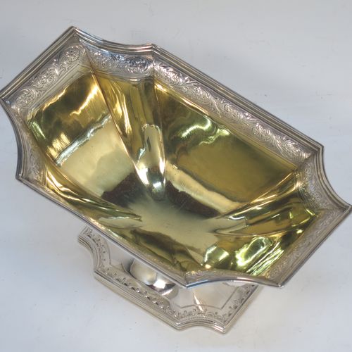 A lovely Antique Georgian Sterling Silver sugar basket, having a shaped rectangular and panelled  body with cut-corners, an applied reeded top border above a band of hand-engraved floral and scroll decoration, a gold-gilt interior, and sitting on a matching pedestal foot. Made by William Frisbee of London in 1794. The dimensions of this fine hand-made antique silver sugar basket are height 14.5 cms (5.75 inches), length 10 cms (4 inches), length 16.5 cms (6.5 inches), width 10 cms (4 inches), and it weighs approx. 258g (8.3 troy ounces).   