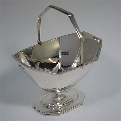 An Antique Edwardian Sterling Silver sugar basket in a Georgian style, having a plain octagonal panelled shaped body, with applied reeded borders, a reeded swing-handle, and sitting on a pedestal foot. Made by Thomas Bradbury and Sons of Sheffield in 1907. The dimensions of this fine hand-made antique silver sugar basket are height 14.5 cms (5.75 inches), length 12.5 cms (5 inches), width 10 cms (4 inches), and it weighs approx. 170g (5.5 troy ounces).    