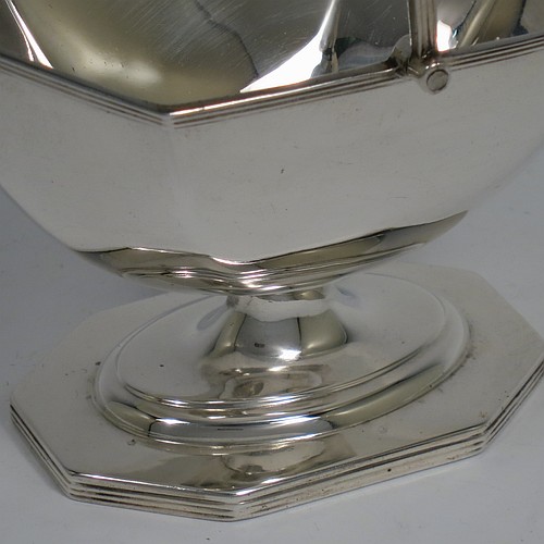 An Antique Edwardian Sterling Silver sugar basket in a Georgian style, having a plain octagonal panelled shaped body, with applied reeded borders, a reeded swing-handle, and sitting on a pedestal foot. Made by Thomas Bradbury and Sons of Sheffield in 1907. The dimensions of this fine hand-made antique silver sugar basket are height 14.5 cms (5.75 inches), length 12.5 cms (5 inches), width 10 cms (4 inches), and it weighs approx. 170g (5.5 troy ounces).    