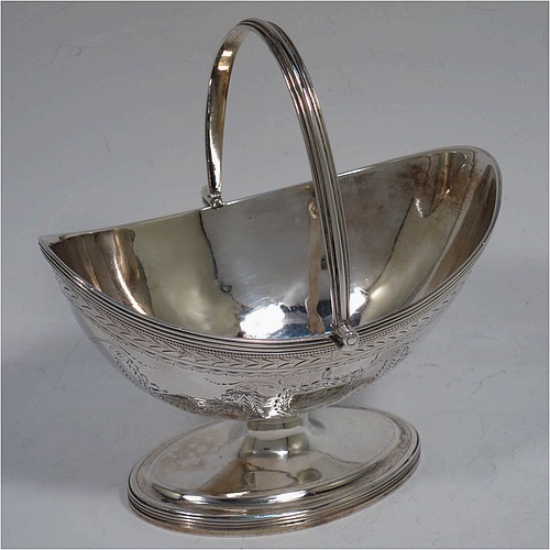 A very pretty Antique Georgian Sterling Silver sugar basket, having an oval bellied body in a Neoclassical style with hand-engraved floral and swag decoration, applied reeded borders, a hinged and reeded swing-handle, and sitting on a pedestal foot. Made by Henry Chawner of London in 1790. The dimensions of this fine hand-made antique silver sugar basket are height (inc. handle) 12.5 cms (5 inches), length 12.5 cms (5 inches), and it weighs approx. 151g (4.9 troy ounces).   