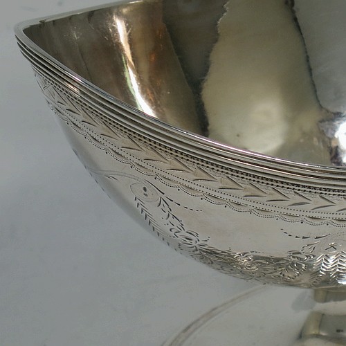 A very pretty Antique Georgian Sterling Silver sugar basket, having an oval bellied body in a Neoclassical style with hand-engraved floral and swag decoration, applied reeded borders, a hinged and reeded swing-handle, and sitting on a pedestal foot. Made by Henry Chawner of London in 1790. The dimensions of this fine hand-made antique silver sugar basket are height (inc. handle) 12.5 cms (5 inches), length 12.5 cms (5 inches), and it weighs approx. 151g (4.9 troy ounces).   