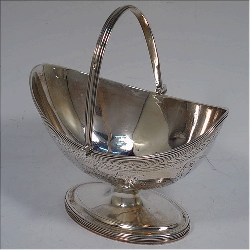 A very pretty Antique Georgian Sterling Silver sugar basket, having an oval bellied body in a Neoclassical style with hand-engraved floral and swag decoration, applied reeded borders, a hinged and reeded swing-handle, and sitting on a pedestal foot. Made by Henry Chawner of London in 1790. The dimensions of this fine hand-made antique silver sugar basket are height (inc. handle) 12.5 cms (5 inches), length 12.5 cms (5 inches), and it weighs approx. 151g (4.9 troy ounces).   