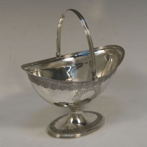 A very elegant and large Antique Georgian Sterling Silver sugar basket, having an oval body with tapering sides and hand-engraved neoclassical style decoration above two vacant cartouches on either side, with applied reeded borders, a hinged and reeded swing-handle, and sitting on a pedestal foot with matching decoration. This beautiful antique silver sweet-meat basket was made by Henry Chawner of London in 1795. The dimensions of this fine hand-made antique silver sugar basket are height (inc. handle) 18.5 cms (7.25 inches), length 16.5 cms (6.5 inches), and it weighs approx. 217g (7 troy ounces).   