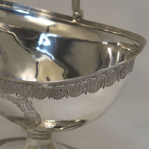 A very elegant and large Antique Georgian Sterling Silver sugar basket, having an oval body with tapering sides and hand-engraved neoclassical style decoration above two vacant cartouches on either side, with applied reeded borders, a hinged and reeded swing-handle, and sitting on a pedestal foot with matching decoration. This beautiful antique silver sweet-meat basket was made by Henry Chawner of London in 1795. The dimensions of this fine hand-made antique silver sugar basket are height (inc. handle) 18.5 cms (7.25 inches), length 16.5 cms (6.5 inches), and it weighs approx. 217g (7 troy ounces).   