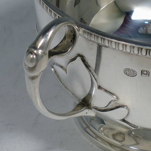 An Antique Sterling Silver sugar bowl, in a Georgian style, having a round bellied body, with unusual applied cut-card work and a gadroon border, two scroll side-handles, and all sitting on a pedestal foot. Made by Alexander Clarke & Co., of Birmingham 1913. The dimensions of this fine hand-made silver sugar bowl are height 7 cms (2.75 inches), spread across handles 15 cms (6 inches), and it weighs approx. 233g (7.5 troy ounces).    