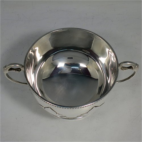 An Antique Sterling Silver sugar bowl, in a Georgian style, having a round bellied body, with unusual applied cut-card work and a gadroon border, two scroll side-handles, and all sitting on a pedestal foot. Made by Alexander Clarke & Co., of Birmingham 1913. The dimensions of this fine hand-made silver sugar bowl are height 7 cms (2.75 inches), spread across handles 15 cms (6 inches), and it weighs approx. 233g (7.5 troy ounces).    