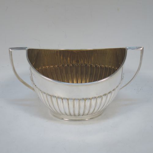 A handsome Antique Edwardian Sterling Silver sugar bowl in a Queen Anne style, having an oval body with hand-chased half-fluted decoration and a gold-gilt interior, two side handles with reeded decoration, and sitting on a collet foot. Made by Goldsmiths and Silversmiths of London in 1908. The dimensions of this fine hand-made antique silver sugar bowl are length 15 cms (6 inches), width 9.5 cms (3.75 inches), height eight 8.5 cms (3.3 inches), and it weighs approx. 157g (5 troy ounces).