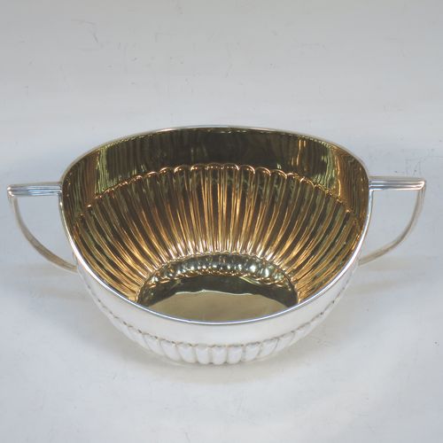 A handsome Antique Edwardian Sterling Silver sugar bowl in a Queen Anne style, having an oval body with hand-chased half-fluted decoration and a gold-gilt interior, two side handles with reeded decoration, and sitting on a collet foot. Made by Goldsmiths and Silversmiths of London in 1908. The dimensions of this fine hand-made antique silver sugar bowl are length 15 cms (6 inches), width 9.5 cms (3.75 inches), height eight 8.5 cms (3.3 inches), and it weighs approx. 157g (5 troy ounces).