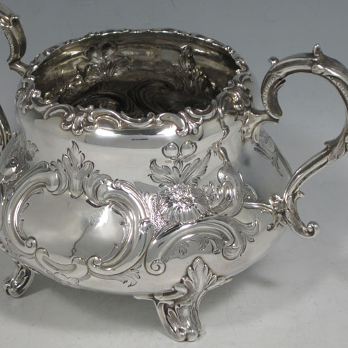 Antique Victorian sterling silver sugar bowl, having a round bellied hand-chased body with floral decoration, scroll handles, and sitting on scroll feet. Made by Martin Hall & Co., of Sheffield in 1856. The dimensions of this fine hand-made silver sugar bowl are height 13.5 cms (5.25 inches), width 22 cms (8.6 inches), and it weighs approx. 436g (14 troy ounces).