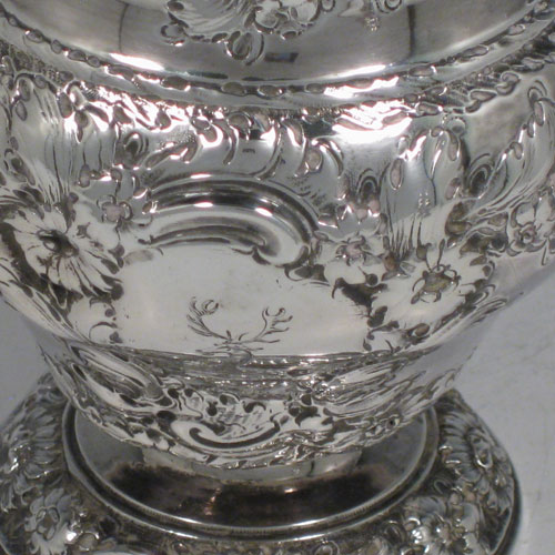 Antique Georgian sterling silver pair of sugar casters, having round baluster shape hand-chased bodies with floral decoration, with pierced pull-off lids and cast finials, all sitting on matching pedestal feet. Made by Samuel Taylor of London in 1750. The dimensions of these fine hand-made silver sugar casters are height 14 cms (5.5 inches), diameter of body 8 cms (3 inches), and they weigh a total of approx. 460g (14.8 troy ounces). Please note that they are both crested and that the lids are not hallmarked. These may have originally been made as a pair of tea caddies with lids pierced at a later date.