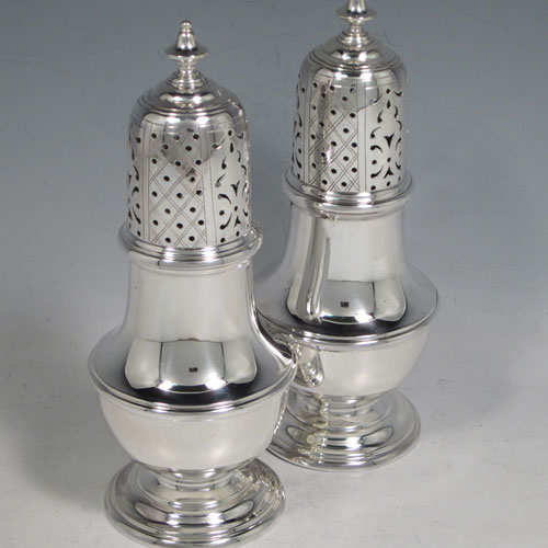 Sterling silver pair of large sugar casters in a George II style, having plain baluster bodies, pull-off hand-pierced lids with urn finials, and sitting on pedestal feet. Made by C. J. Vander of London in 1960. The dimensions of this fine pair of hand-made silver sugar casters are height 18 cms (7 inches), width 7 cms (2.75 inches), with a total weight of approx. 375g (12 troy ounces).