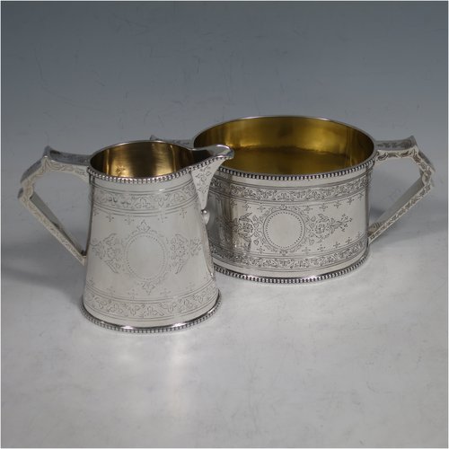 An Antique Victorian Sterling silver sugar and creamer set, having oval bodies with hand-engraved floral decoration, applied beaded borders, gold-gilt interiors, and angular handles. Made by Goldsmiths & Silversmiths of London in 1881. The dimensions of this fine hand-made antique silver cream and sugar set are height of creamer 9 cms (3.5 inches), length of sugar bowl 16 cms (6.25 inches), and with a total weight approx. 303g (9.8 troy ounces).   