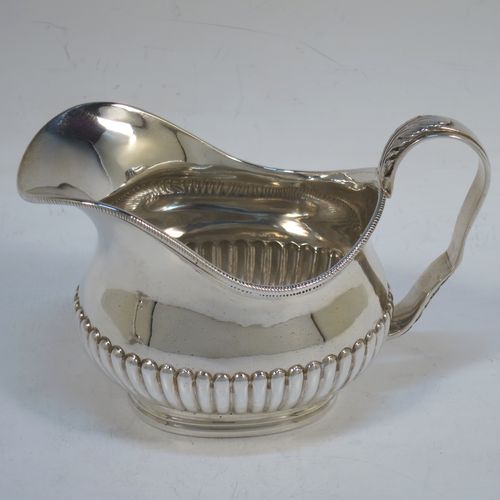 A pretty Antique Victorian Sterling Silver sugar bowl and cream jug set, having oval bellied bodies with hand-chased half-fluted decoration, applied rope-twist  borders, scroll side-handles with anthemion leaf thumb-pieces, and all sitting on collet feet. Made by Frederick Bradford Macrea of London in 1887. The dimensions of this fine hand-made antique silver sugar and creamer set are length of sugar bowl (inc. handles) 16.5 cms (6.5 inches), height 9 cms (3.5 inches), width 9.5 cms (3.75 inches), and with a total weight of approx. 310g (10 troy ounces).  