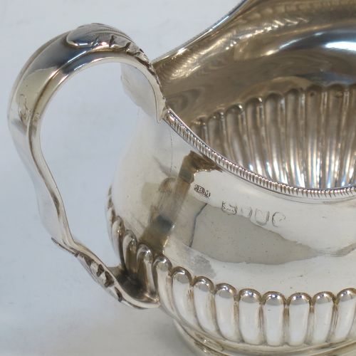 A pretty Antique Victorian Sterling Silver sugar bowl and cream jug set, having oval bellied bodies with hand-chased half-fluted decoration, applied rope-twist  borders, scroll side-handles with anthemion leaf thumb-pieces, and all sitting on collet feet. Made by Frederick Bradford Macrea of London in 1887. The dimensions of this fine hand-made antique silver sugar and creamer set are length of sugar bowl (inc. handles) 16.5 cms (6.5 inches), height 9 cms (3.5 inches), width 9.5 cms (3.75 inches), and with a total weight of approx. 310g (10 troy ounces).  