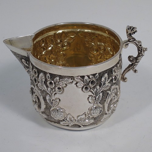 A beautiful Antique Victorian Sterling Silver sugar and creamer set, having round bodies with hand-chased floral decoration, and with gold-gilt interiors, all sitting on flat bases. Made by James Wakely & Frank Clarke Wheeler of London in 1890. The dimensions of this fine hand-made antique silver sugar and creamer set are diameter of sugar bowl 8 cms (3 inches), height of cream jug 6.5 cms (2.5 inches), and with a total weight of 133g (4.3 troy ounces).    