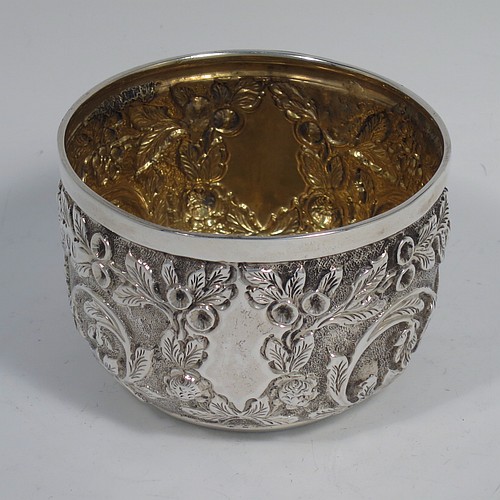 A beautiful Antique Victorian Sterling Silver sugar and creamer set, having round bodies with hand-chased floral decoration, and with gold-gilt interiors, all sitting on flat bases. Made by James Wakely & Frank Clarke Wheeler of London in 1890. The dimensions of this fine hand-made antique silver sugar and creamer set are diameter of sugar bowl 8 cms (3 inches), height of cream jug 6.5 cms (2.5 inches), and with a total weight of 133g (4.3 troy ounces).    