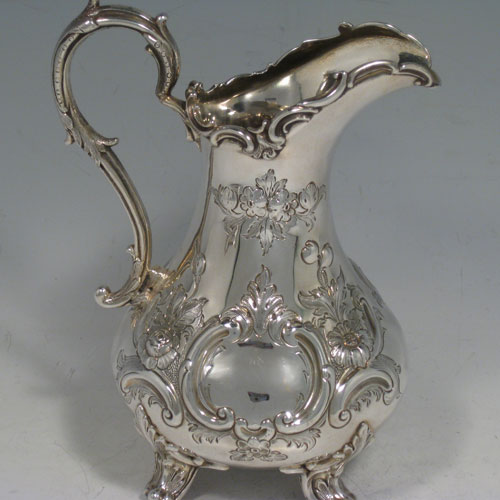 Antique Victorian sterling silver sugar and cream set, having round bellied hand-chased bodies with floral decoration, scroll handles, and sitting on scroll feet. Made by Martin Hall & Co., of Sheffield in 1856. The dimensions of this fine hand-made silver sugar and cream set are height of cream jug 16.5 cms (6.5 inches), width of sugar bowl 22 cms (8.6 inches), with a total weight of approx. 730g (23.5 troy ounces).