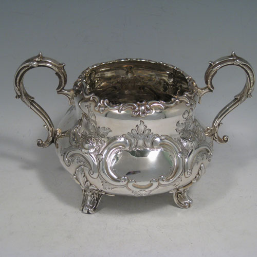 Antique Victorian sterling silver sugar and cream set, having round bellied hand-chased bodies with floral decoration, scroll handles, and sitting on scroll feet. Made by Martin Hall & Co., of Sheffield in 1856. The dimensions of this fine hand-made silver sugar and cream set are height of cream jug 16.5 cms (6.5 inches), width of sugar bowl 22 cms (8.6 inches), with a total weight of approx. 730g (23.5 troy ounces).