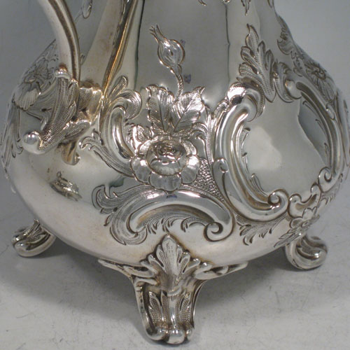 Antique Victorian sterling silver sugar and cream set, having round bellied hand-chased bodies with floral decoration, scroll handles, and sitting on scroll feet. Made by Martin Hall & Co., of Sheffield in 1856. The dimensions of this fine hand-made silver sugar and cream set are height of cream jug 16.5 cms (6.5 inches), width of sugar bowl 22 cms (8.6 inches), with a total weight of approx. 730g (23.5 troy ounces).