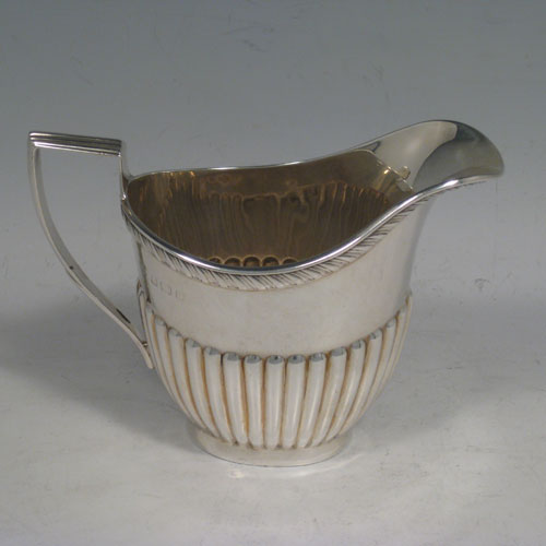 Antique Edwardian sterling silver sugar and creamer set, having oval bodies with hand-chased half-fluted decoration, applied gadroon borders, and reeded handles. Made by William Aitken of Birmingham in 1902. Height 10 cms (4 inches), length of sugar bowl 19 cms (7.5 inches). Total weight approx. 419g (13.5 troy ounces).