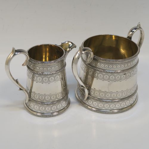 A large, beautiful and heavy Antique Victorian Sterling Silver sugar and creamer set, having round bodies with tapering sides and hand-engraved bright-cut floral decoration, with applied beaded borders, gold-gilt interiors, cast scroll side-handles, and all sitting on flat bases. This very pretty sugar and cream set was made by the Bradbury Brothers of London in 1869. The dimensions of this fine hand-made antique silver cream and sugar set are height of creamer 11.5 cms (4.5 inches), diameter of sugar bowl 10 cms (4 inches), and with a total weight approx. 639g (21 troy ounces).  