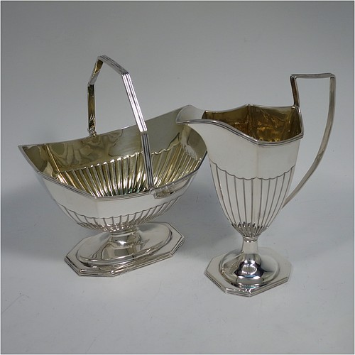 An Antique Victorian Sterling Silver sugar basket and cream jug set, having Neoclassical style panelled bodies with hand-chased half-fluted decoration, with applied reeded borders and gold-gilt interiors, the sugar basket with a swing-handle, and all sitting on pedestal feet. Made by Thomas Bradbury of London in 1897. The dimensions of this fine hand-made antique silver sugar and creamer set are height of cream jug 12.5 cms (5 inches), length of sugar basket 12.5 cms (5 inches), with a total weight of approx. 256g (8.3 troy ounces).    