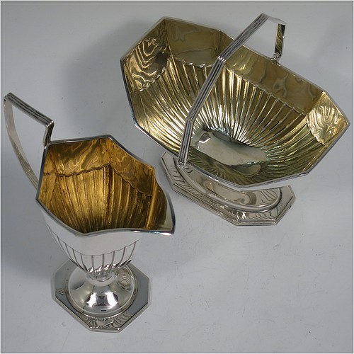 An Antique Victorian Sterling Silver sugar basket and cream jug set, having Neoclassical style panelled bodies with hand-chased half-fluted decoration, with applied reeded borders and gold-gilt interiors, the sugar basket with a swing-handle, and all sitting on pedestal feet. Made by Thomas Bradbury of London in 1897. The dimensions of this fine hand-made antique silver sugar and creamer set are height of cream jug 12.5 cms (5 inches), length of sugar basket 12.5 cms (5 inches), with a total weight of approx. 256g (8.3 troy ounces).    