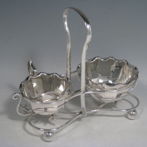 Sterling silver sugar and cream set in a frame, having round panelled bodies with scroll edges, and flat bases, all sitting in an original wire-work frame on four ball feet. Made by James Dixon and Sons of Sheffield in 1913. Height 18 cms (7 inches), length 22 cms (8.5 inches), width 12.5 cms (5 inches). Total weight 495g (16 troy ounces)