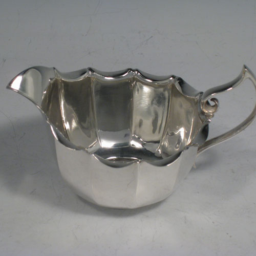 Sterling silver sugar and cream set in a frame, having round panelled bodies with scroll edges, and flat bases, all sitting in an original wire-work frame on four ball feet. Made by James Dixon and Sons of Sheffield in 1913. Height 18 cms (7 inches), length 22 cms (8.5 inches), width 12.5 cms (5 inches). Total weight 495g (16 troy ounces)