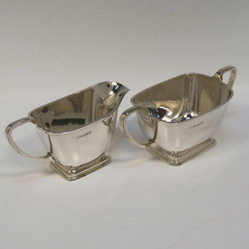 A heavy and elegant Sterling Silver pair of Art Deco sugar bowl and creamer set, having plain rectangular bodies with tapering sides and rounded corners, with cast scroll side-handles, and all sitting on pedestal feet. This handsome silver sugar and cream set was made by Charles Fletcher  of Sheffield in 1939. The dimensions of this fine hand-made silver Art Deco style sugar bowl and cream jug set are height of cream jug 8 cms (3 inches), width of sugar bowl (inc. handles) 18 cms (7 inches), and the total weight is approx. 461g (14.9 troy ounces).   