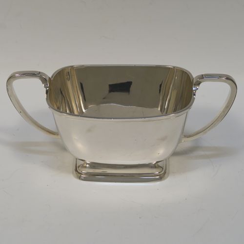 A heavy and elegant Sterling Silver pair of Art Deco sugar bowl and creamer set, having plain rectangular bodies with tapering sides and rounded corners, with cast scroll side-handles, and all sitting on pedestal feet. This handsome silver sugar and cream set was made by Charles Fletcher  of Sheffield in 1939. The dimensions of this fine hand-made silver Art Deco style sugar bowl and cream jug set are height of cream jug 8 cms (3 inches), width of sugar bowl (inc. handles) 18 cms (7 inches), and the total weight is approx. 461g (14.9 troy ounces).   