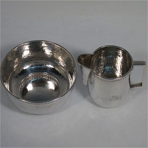 A very attractive Arts and Crafts Sterling Silver sugar and creamer set, having round bodies with hand-hammered plenished decoration, with applied reeded and rope-twist top borders, all sitting on flat bases. Made by Edward Spencer of the Artificiers Guild of London in 1928. The dimensions of this fine hand-made Arts and Crafts  silver sugar and creamer set are diameter of sugar bowl 9 cms (3.5 inches), height of cream jug 7 cms (2.75 inches), with a total weight of 173g (5.6 troy ounces).    