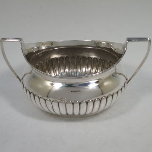 A very handsome Antique Georgian Irish Sterling Silver sugar bowl and cream jug set, having oval bellied bodies with hand-chased half-fluted decoration, applied reeded borders and flat-topped side-handles, and all sitting on collet feet. Made by James Scott of Dublin in 1806. The dimensions of this fine hand-made antique Irish silver sugar and creamer set are length of sugar bowl (inc. handles) 20 cms (8 inches), height 10 cms (4 inches), width 13 cms (5 inches), with a total weight of approx. 436g (14 troy ounces).    