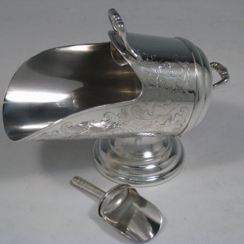 Antique Victorian silver-plated sugar scuttle, having a hand-engraved body with floral decoration, two cast scroll handles, an original scoop, and sitting on a pedestal foot. Made in ca. 1890. The dimensions of this fine hand-made silver-plated sugar scuttle are length 15 cms (6 inches), height 11.5 cms (4.5 inches), and width 7.5 cms (3 inches).   