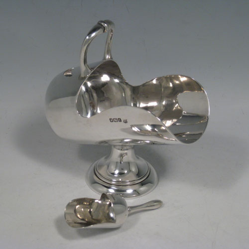 Antique Edwardian sterling silver sugar scuttle, having a plain body, a cast scroll handle, an original scoop, and sitting on a pedestal foot. Made by the Deakin Brothers of Sheffield in 1909. The dimensions of this fine hand-made silver sugar scuttle are length 16 cms (6.25 inches), height 14 cms (5.5 inches), width 7 cms (2.75 inches), and it weighs approx. 256g (8 troy ounces).