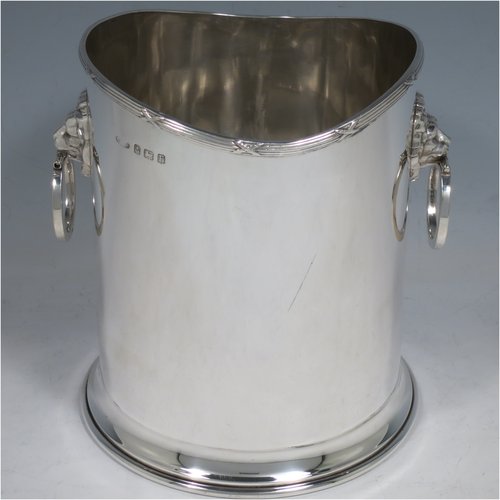 A Sterling Silver syphon stand, having a plain cylindrical body, two side-hinged ring handles with lion mask mounts, an applied reed and ribbon border, and sitting on a plain collet foot. Made by Britton, Gould & Co., of Birmingham in 1930. The dimensions of this fine hand-made silver siphon stand are diameter 13 cms (5 inches), height 14 cms (5.5 inches), and it weighs approx. 420g (13.5 troy ounces).   