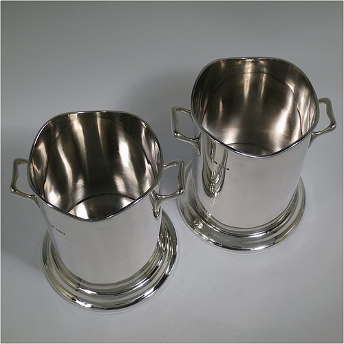 A Sterling Silver pair of syphon stands or champagne / wine bottle holders, having plain round bodies with straight sides, with two cast scroll side-handles, applied wavey-edge reeded borders, and sitting on collet feet. Made by Emile Viner of Sheffield in 1932/33. The dimensions of these fine hand-made silver wine / champagne bottle holders or siphon stands are diameter 12 cms (4.75 inches), height 17 cms (6.75 inches), and they weigh a total of  approx. 1,296g (42 troy ounces).   