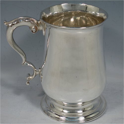 An Antique Georgian George III Sterling Silver pint tankard or mug, having a plain round bellied body, a scroll handle with an anthemion-leaf thumb-piece, and sitting on a pedestal foot. Made by John King of London in 1773. The dimensions of this fine hand-made antique silver pint mug or tankard are height 12.5 cms (5 inches), diameter at top 8 cms (3 inches), and it weighs approx. 317g (10.2 troy ounces).    