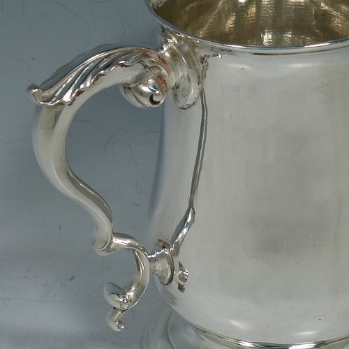 An Antique Georgian George III Sterling Silver pint tankard or mug, having a plain round bellied body, a scroll handle with an anthemion-leaf thumb-piece, and sitting on a pedestal foot. Made by John King of London in 1773. The dimensions of this fine hand-made antique silver pint mug or tankard are height 12.5 cms (5 inches), diameter at top 8 cms (3 inches), and it weighs approx. 317g (10.2 troy ounces).    