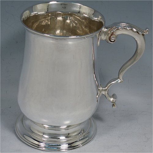 An Antique Georgian George III Sterling Silver pint tankard or mug, having a plain round bellied body, a scroll handle with an anthemion-leaf thumb-piece, and sitting on a pedestal foot. Made by John King of London in 1773. The dimensions of this fine hand-made antique silver pint mug or tankard are height 12.5 cms (5 inches), diameter at top 8 cms (3 inches), and it weighs approx. 317g (10.2 troy ounces).    