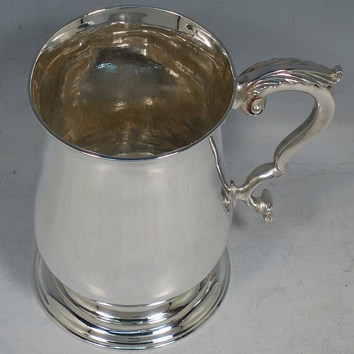 An Antique Georgian George III Sterling Silver pint tankard or mug, having a plain round bellied body, a scroll handle with an anthemion-leaf thumb-piece, and sitting on a pedestal foot. Made by John King of London in 1773. The dimensions of this fine hand-made antique silver pint mug or tankard are height 12.5 cms (5 inches), diameter at top 8 cms (3 inches), and it weighs approx. 317g (10.2 troy ounces).    