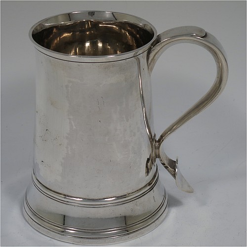 An Antique Georgian Sterling Silver pint tankard, having a plain round straight-sided body with hand-chased reeded borders, a scroll handle with heart-shaped terminal, and sitting on a collet foot. Made by Peter and William Bateman of London in 1804. The dimensions of this fine hand-made antique silver tankard are height 12 cms (4.75 inches), diameter at top 7.5 cms (3 inches), and it weighs approx. 315g (10.2 troy ounces).   